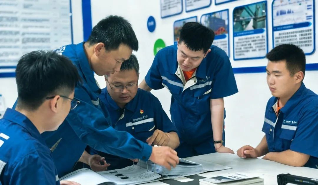 السيد سونغ (يسار 3) مع زملائه يناقشون إمكانية الحل في اجتماع.